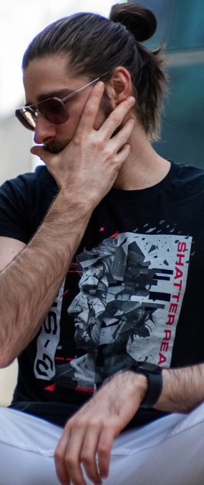 Mike Bello close-up sitting in the city wearing a black B-Side T-shirt and sunglasses